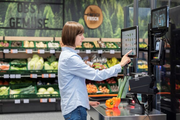 Kundin wiegt Paprika an Self-Checkout Kasse