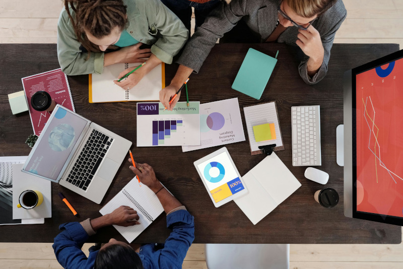 Tisch mit drei Personen, die Power-BI Grundlagen besprechen