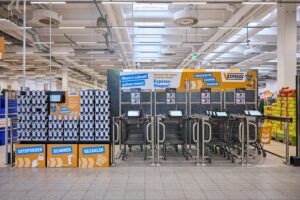 Foto vom Eingangsbereich des V-Markts mit smarten Einkaufswagen und mobilen Scannern