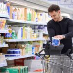 Kunde scannt Joghurt mit Scanner am Einkaufswagen